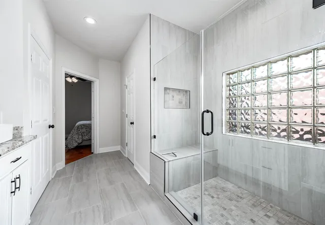 a en suite bathroom with a granite countertop sink a mirror and shower
