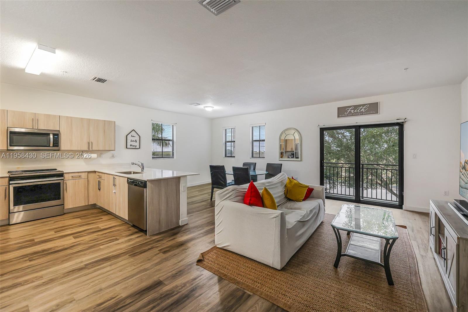a living room with stainless steel appliances furniture and a kitchen view