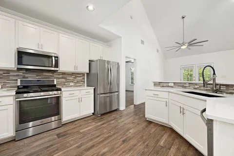a kitchen with appliances a sink cabinets and wooden floor
