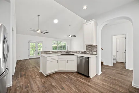 a kitchen with stainless steel appliances granite countertop a stove a sink dishwasher and a refrigerator with wooden floor
