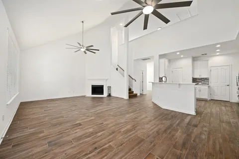 a view of empty room with wooden floor and ceiling fan