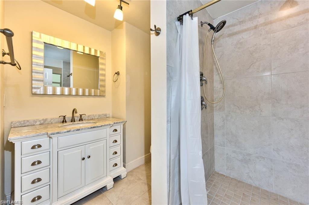 671 98th Avenue North Naples, FL 34108 - Photo 14 of 27 a bathroom with a granite countertop sink a mirror a vanity and a shower