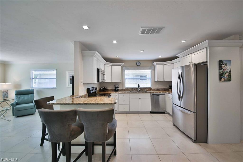 671 98th Avenue North Naples, FL 34108 - Photo 7 of 27 a kitchen with stainless steel appliances granite countertop a refrigerator a sink a stove a dining table and chairs