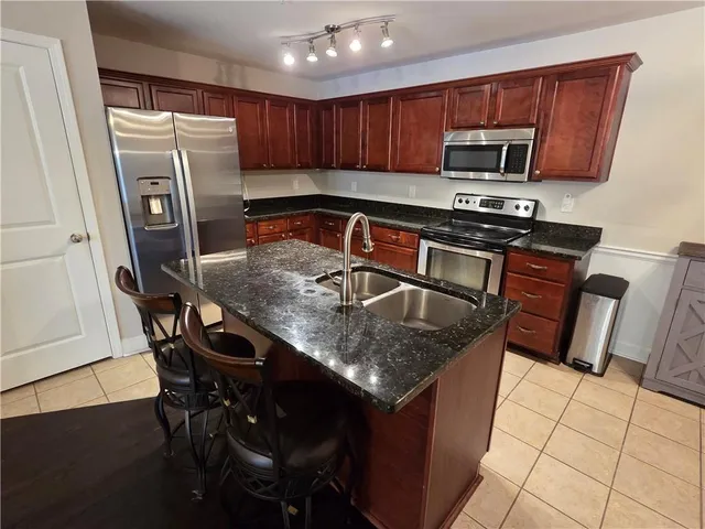 a kitchen with stainless steel appliances granite countertop a table chairs sink refrigerator and microwave