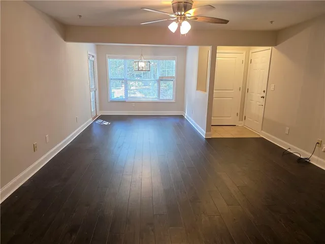 an empty room with wooden floor fan and windows