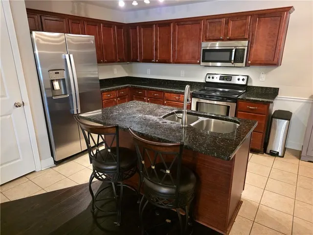 a kitchen with stainless steel appliances granite countertop a stove a refrigerator a sink a dining table and chairs