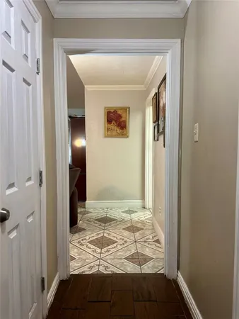a view of a hallway with wooden floor and a bathroom