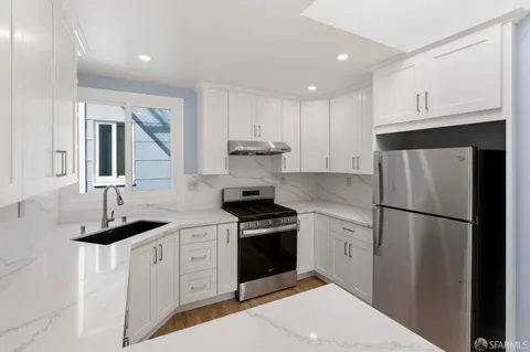 a kitchen with a sink white cabinets and stainless steel appliances