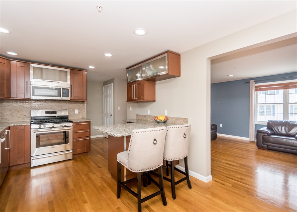 985 Trapelo Road, Unit 23 Waltham, MA 02452 - Photo 8 of 27 a kitchen with stainless steel appliances granite countertop a stove top oven a sink dishwasher a dining table and chairs with wooden floor