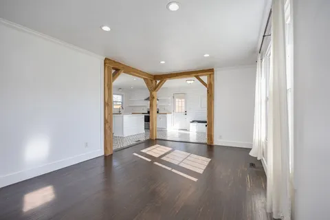 a view of empty room with wooden floor and a window