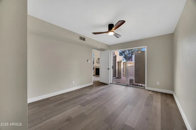 a view of an empty room with wooden floor and a ceiling fan