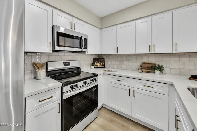 a kitchen with white cabinets and stainless steel appliances