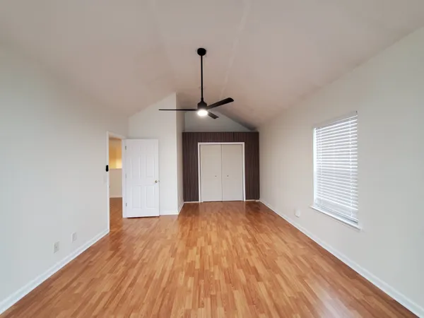 a big room with wooden floor windows and a ceiling fan