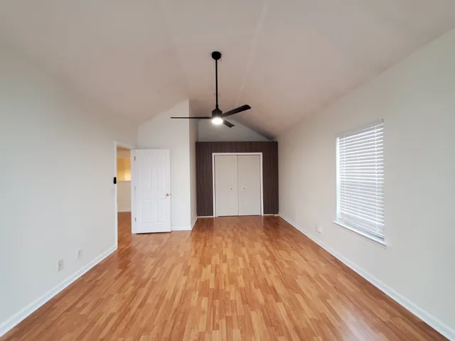 a big room with wooden floor windows and a ceiling fan