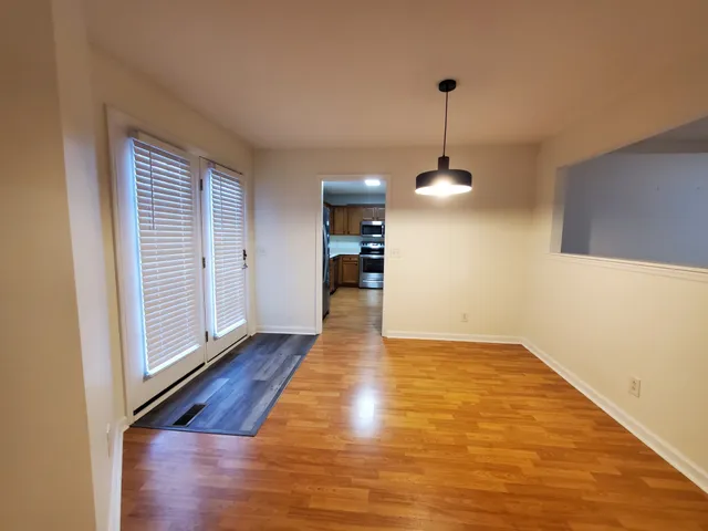 a view of a room with wooden floor chandelier and windows