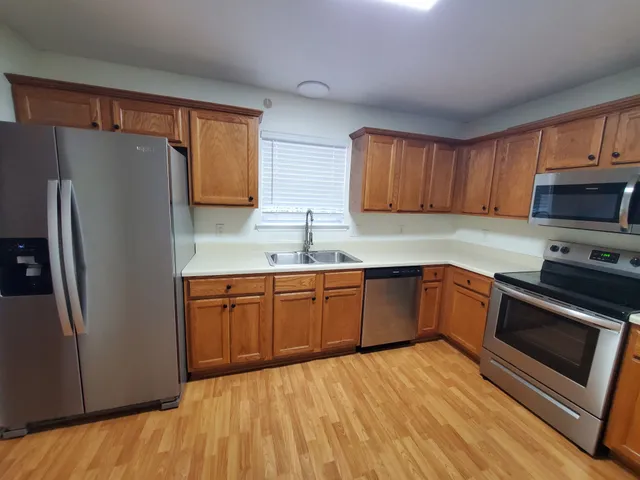 a kitchen with stainless steel appliances granite countertop a refrigerator stove top oven and sink