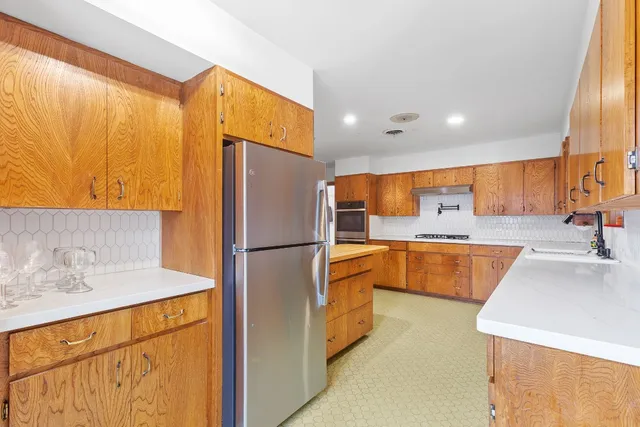 a kitchen with stainless steel appliances granite countertop a refrigerator a sink and a stove