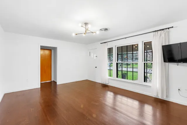 a view of an empty room with a window and wooden floor