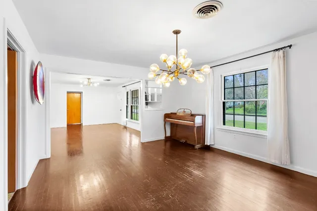 a view of an empty room with window and wooden floor