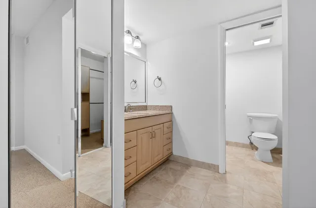 a bathroom with a granite countertop sink mirror and toilet