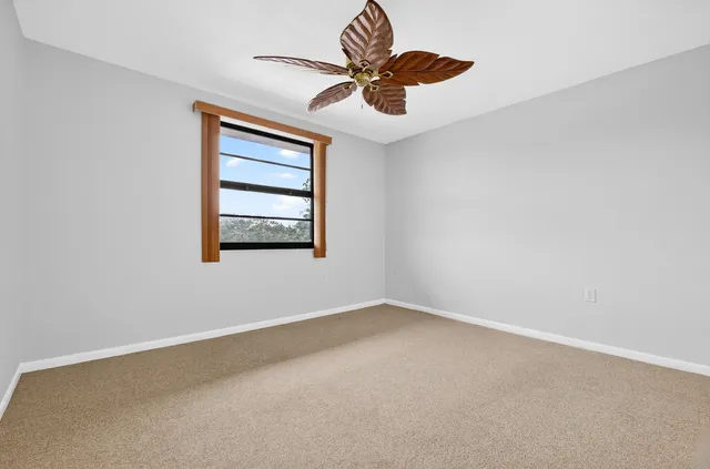 an empty room with a chandelier fan and windows