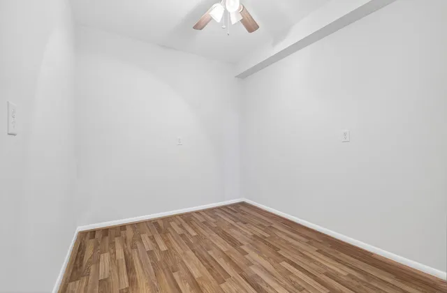 a view of room with wooden floor and a ceiling fan