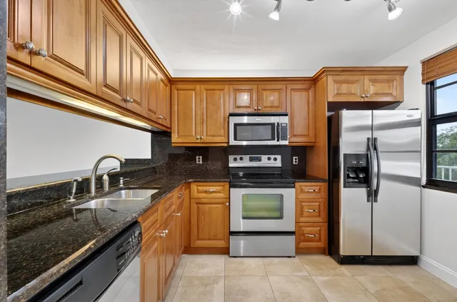 a kitchen with stainless steel appliances granite countertop a stove a sink and a microwave