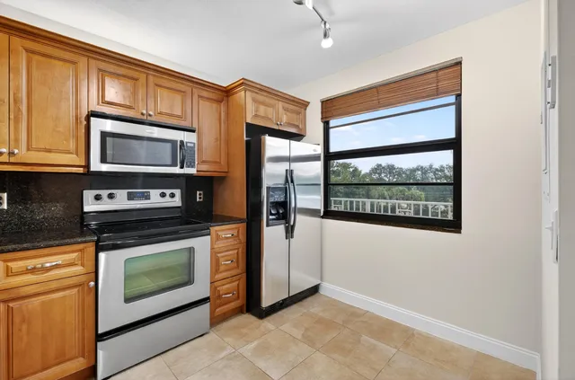 a kitchen with granite countertop wooden cabinets stainless steel appliances and a window