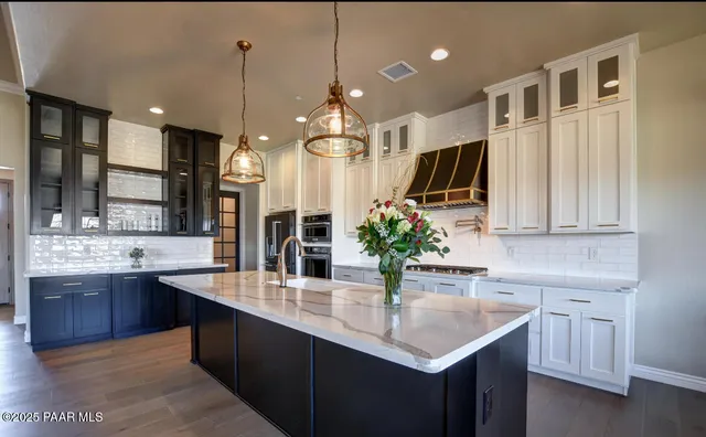 a large living room with stainless steel appliances kitchen island granite countertop a large kitchen island a stove a sink a dining table and chairs with wooden floor