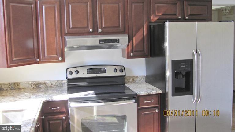 7116 Minna Road Gwynn Oak, MD 21207 - Photo 11 of 12 a kitchen with stainless steel appliances granite countertop a coffee maker and a refrigerator