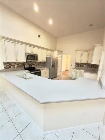 a kitchen with kitchen island granite countertop a sink a counter top space cabinets stainless steel appliances and cabinets