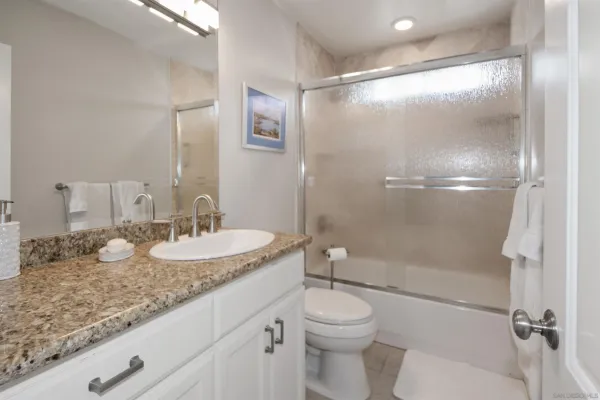 a bathroom with a granite countertop sink toilet mirror and shower