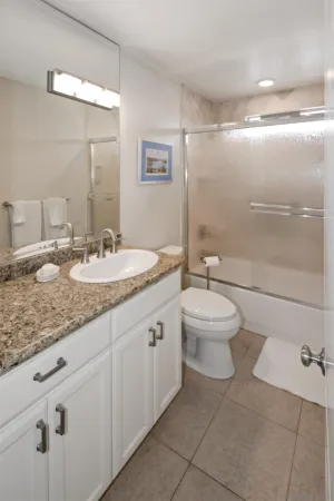 a bathroom with a granite countertop sink mirror vanity and toilet