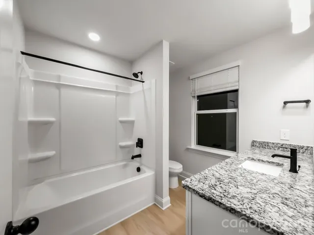 a bathroom with a granite countertop sink a toilet and shower
