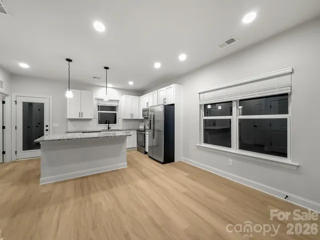 a large kitchen with stainless steel appliances kitchen island a large counter top and a refrigerator