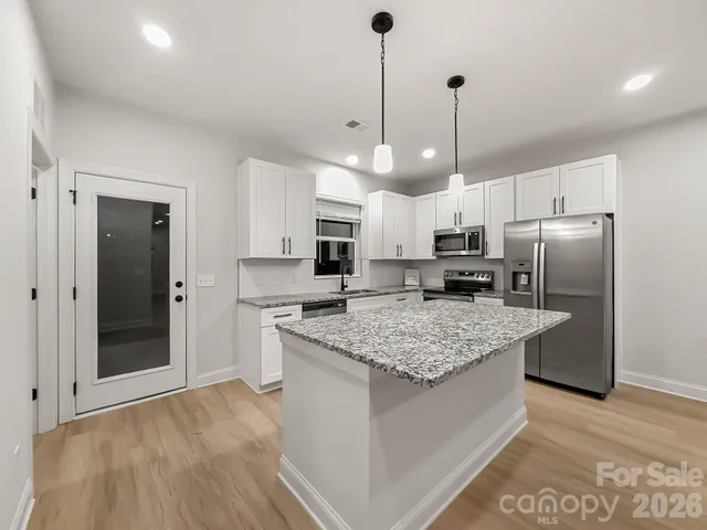 a kitchen with stainless steel appliances granite countertop a sink refrigerator and cabinets