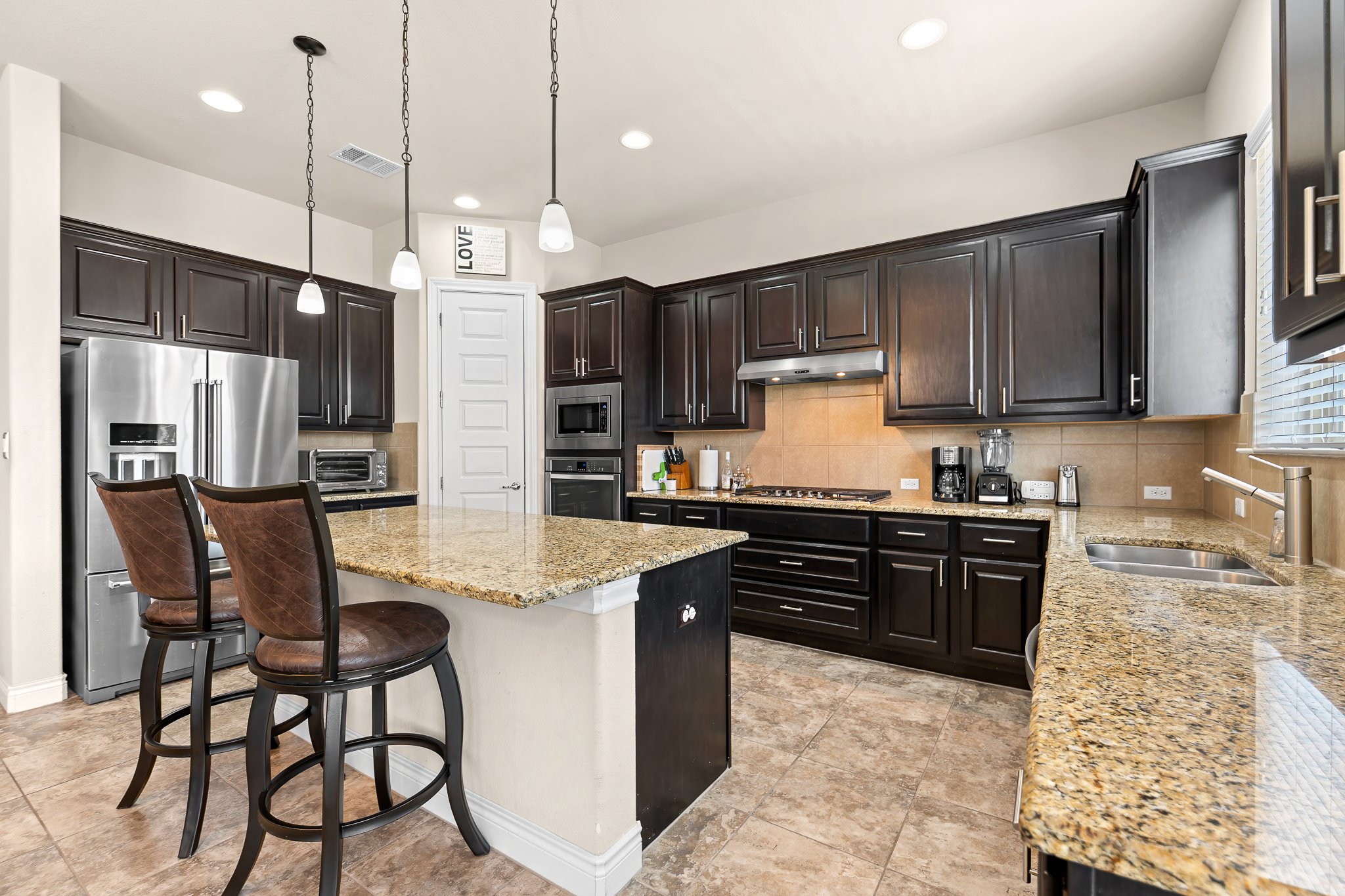 3501 Great Knot Pass Pflugerville, TX 78660 - Photo 13 of 40 a kitchen with stainless steel appliances kitchen island granite countertop a refrigerator a stove a sink a dining table and chairs