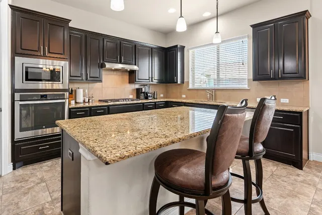 a kitchen with kitchen island granite countertop wooden cabinets and stainless steel appliances