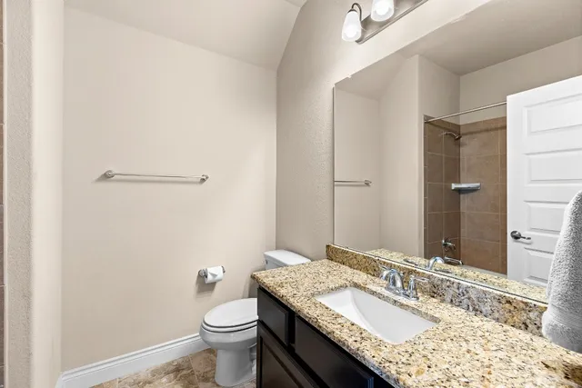 a bathroom with a granite countertop sink a toilet and a mirror