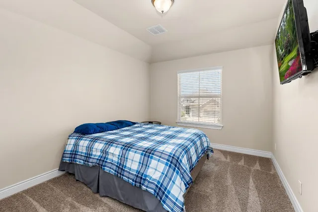 a bedroom with a bed and a flat tv screen on the dresser