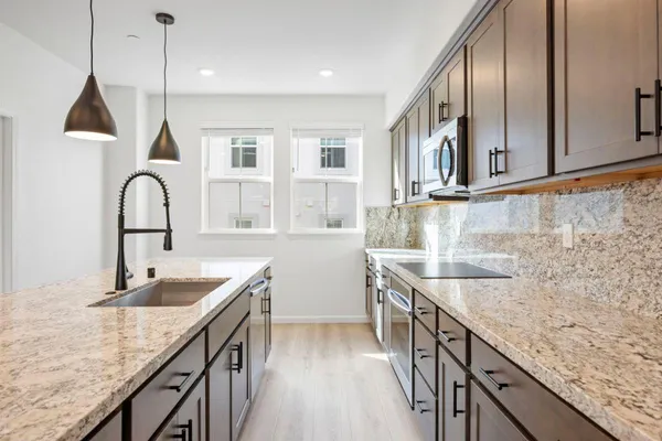 a kitchen with granite countertop a sink a counter space appliances and cabinets