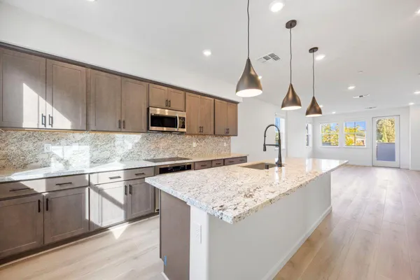a large kitchen with a large counter top a sink stainless steel appliances and cabinets