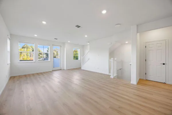 a view of an empty room with a window and wooden floor