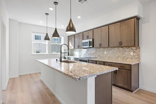 a kitchen with stainless steel appliances granite countertop a sink a oven a counter space and cabinets