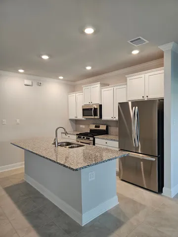 a kitchen with kitchen island a counter top space stainless steel appliances and cabinets