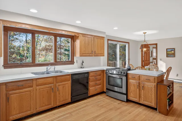 a kitchen with stainless steel appliances granite countertop white cabinets a sink and a large window