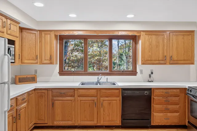 a kitchen with granite countertop wooden cabinets a sink and a window