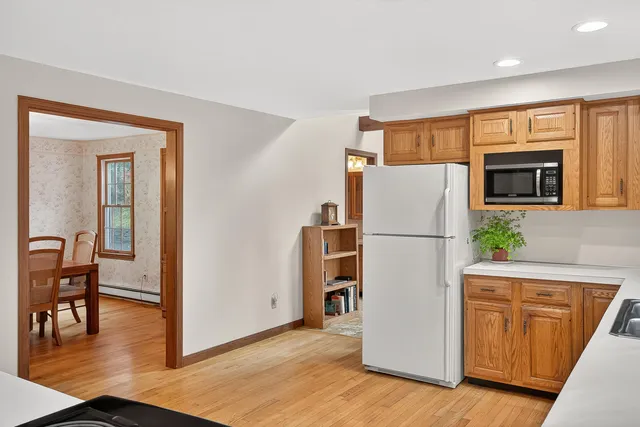 a white refrigerator freezer sitting in a kitchen with stainless steel appliances granite countertop cabinets and wooden floor
