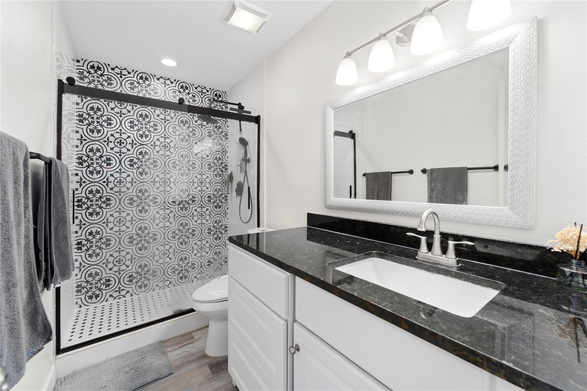 8223 Kingsbrook Road, Unit 212 Houston, TX 77024 - Photo 6 of 10 a bathroom with a granite countertop sink a toilet a mirror and shower