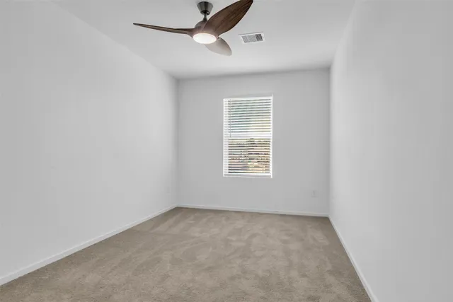 an empty room with a window and ceiling fan